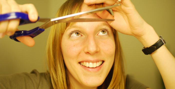 une jeune femme se coupe elle-même les cheveux