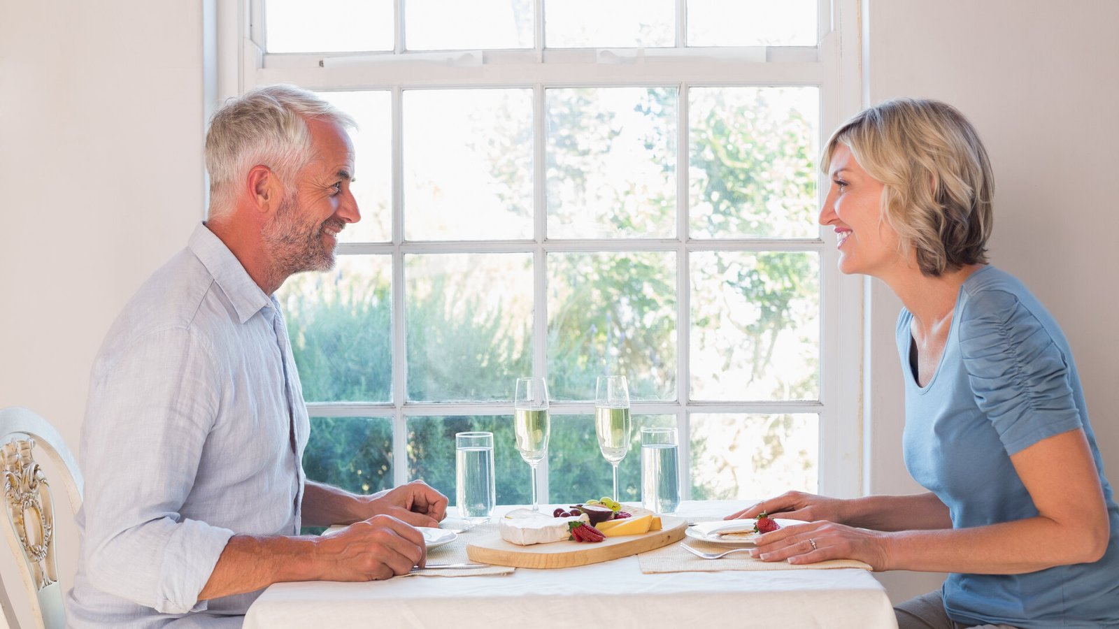 Un couple d'une soixantaine d'années partage un repas près d'une fenêtre