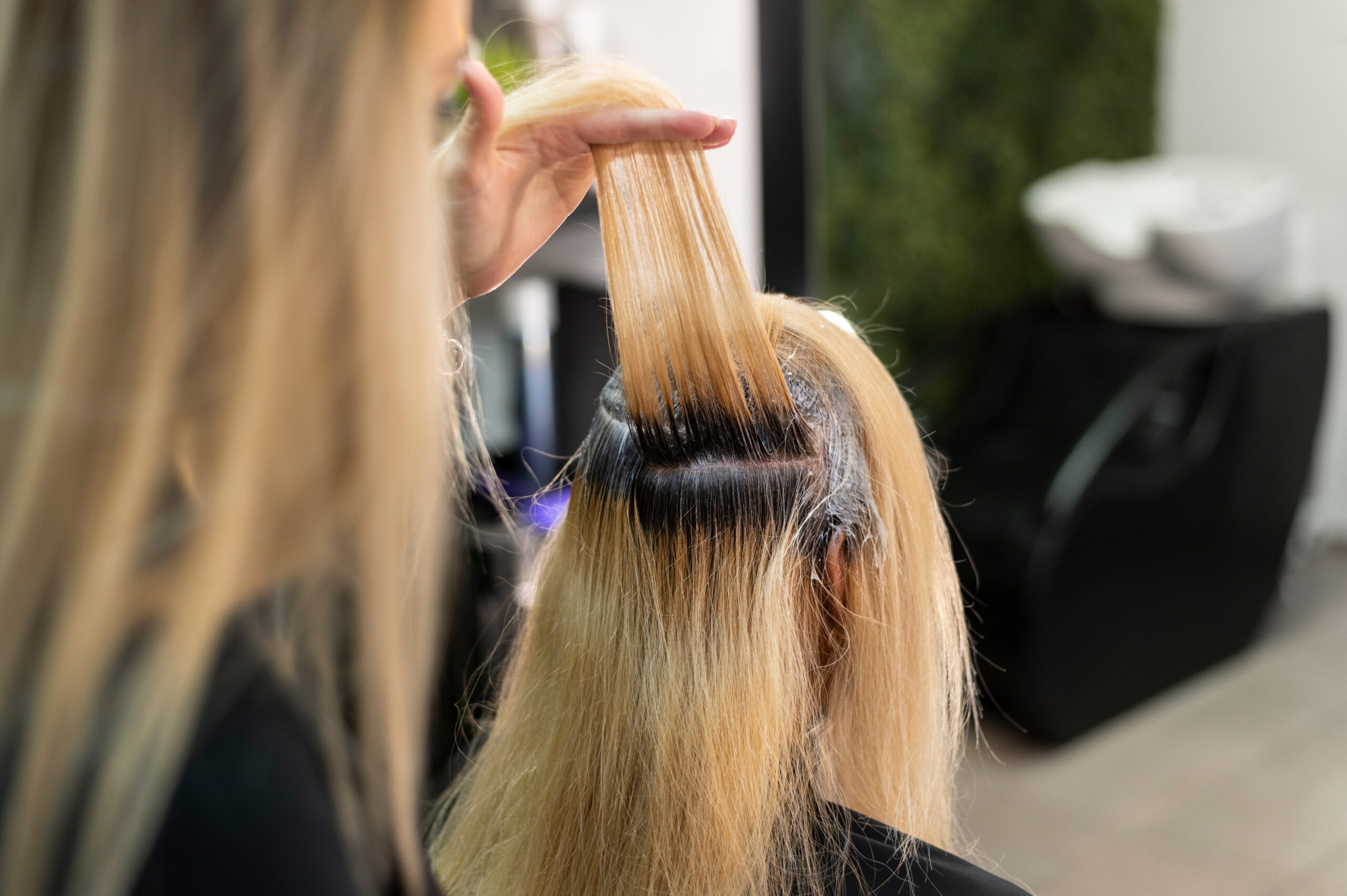 Application d'un soin gloss sur des longueurs en salon de coiffure